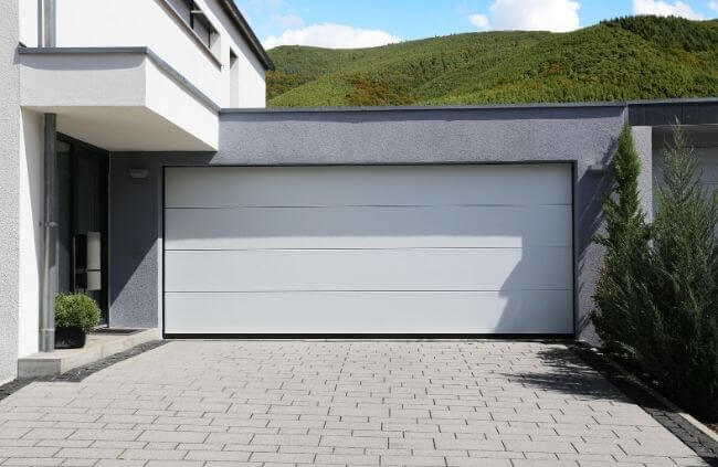 A modern double garage with a clean white sectional door, professional garage door installation, servicing, repairs and replacement by Garage Door Repair Guys.