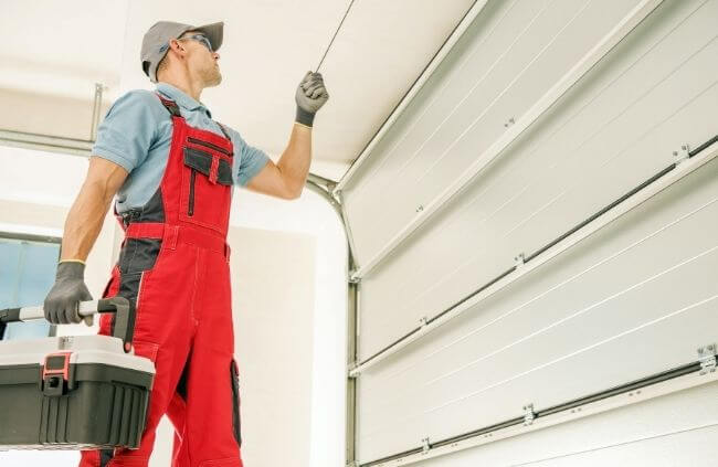 Garage Door Repair Guys carrying out garage door panel replacement with a technician checking the alignment of the new panels.