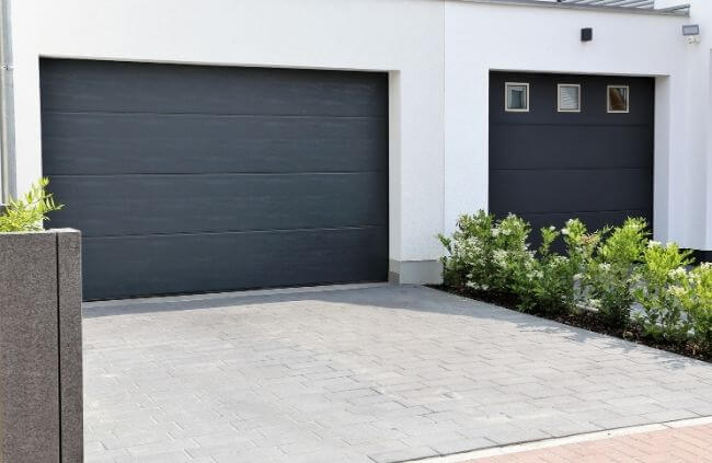 Modern double garage with sleek dark sectional doors, home service call for garage door opener remote replacement by Garage Door Repair Guys