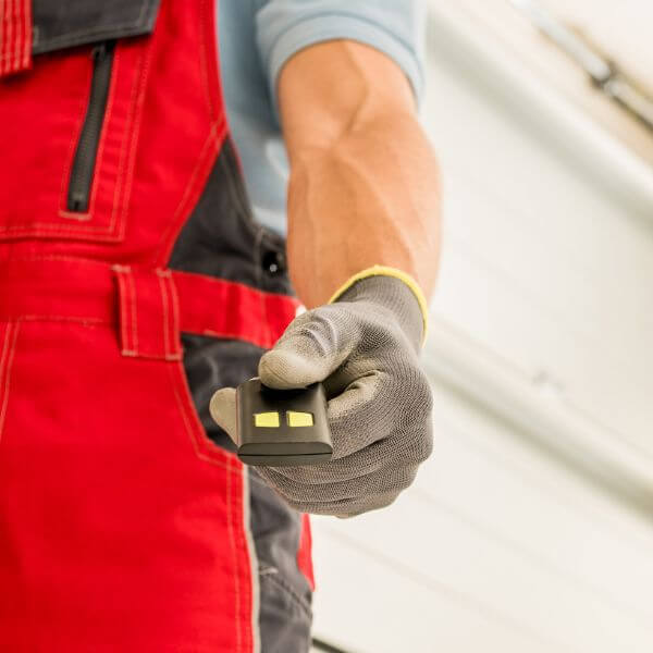 Technician testing a garage door remote control for smooth operation, serviced by Garage Door Repair Guys.