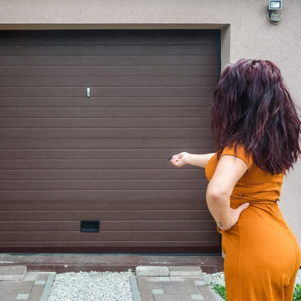 Garage door remote replacement in Melbourne, showing a homeowner testing a new remote after the door failed to respond, serviced by Garage Door Repair Guys.