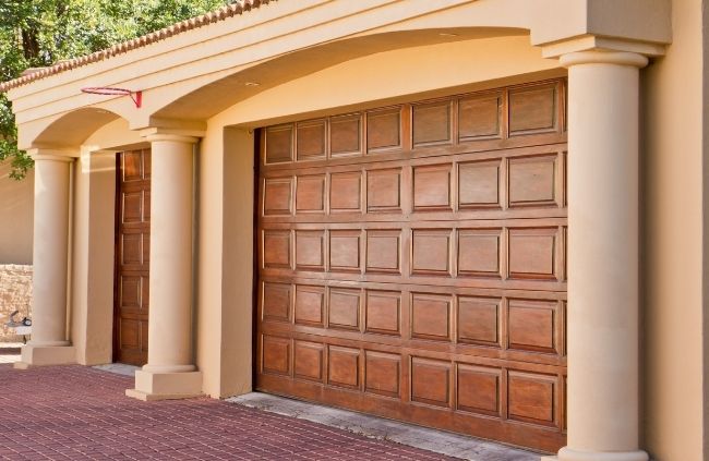 Timber-look garage door replacement on a Mediterranean-style home, delivering a premium, freshly updated finish by Garage Door Repair Guys
